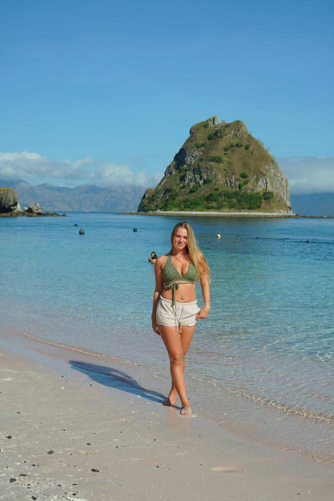 Kelor – woman standing on sand, islet behind (Real photo from a Komodo Explorer trip)