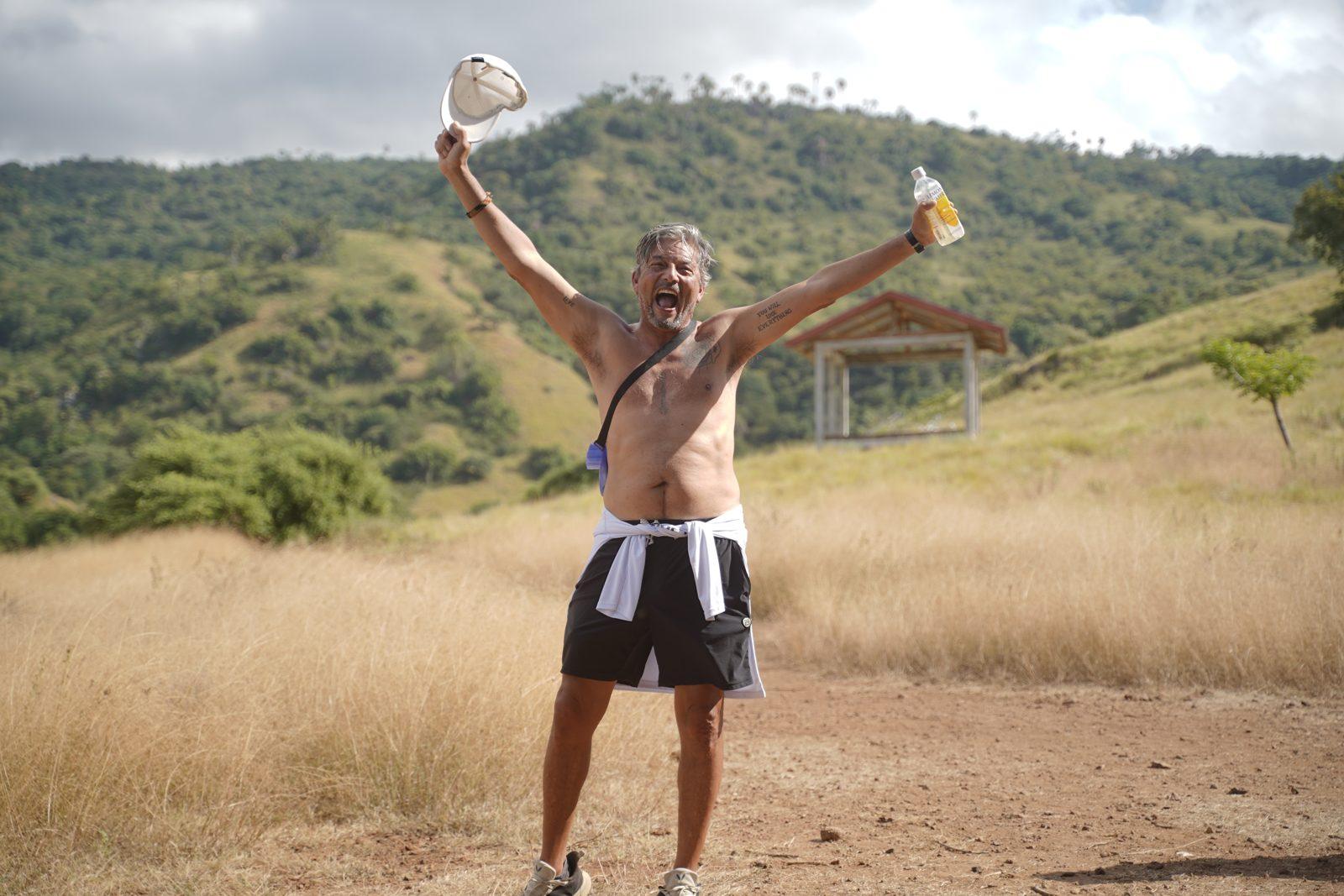 Komodo – Shirtless man cheering on savanna trail (Real photo from a Komodo Explorer trip)