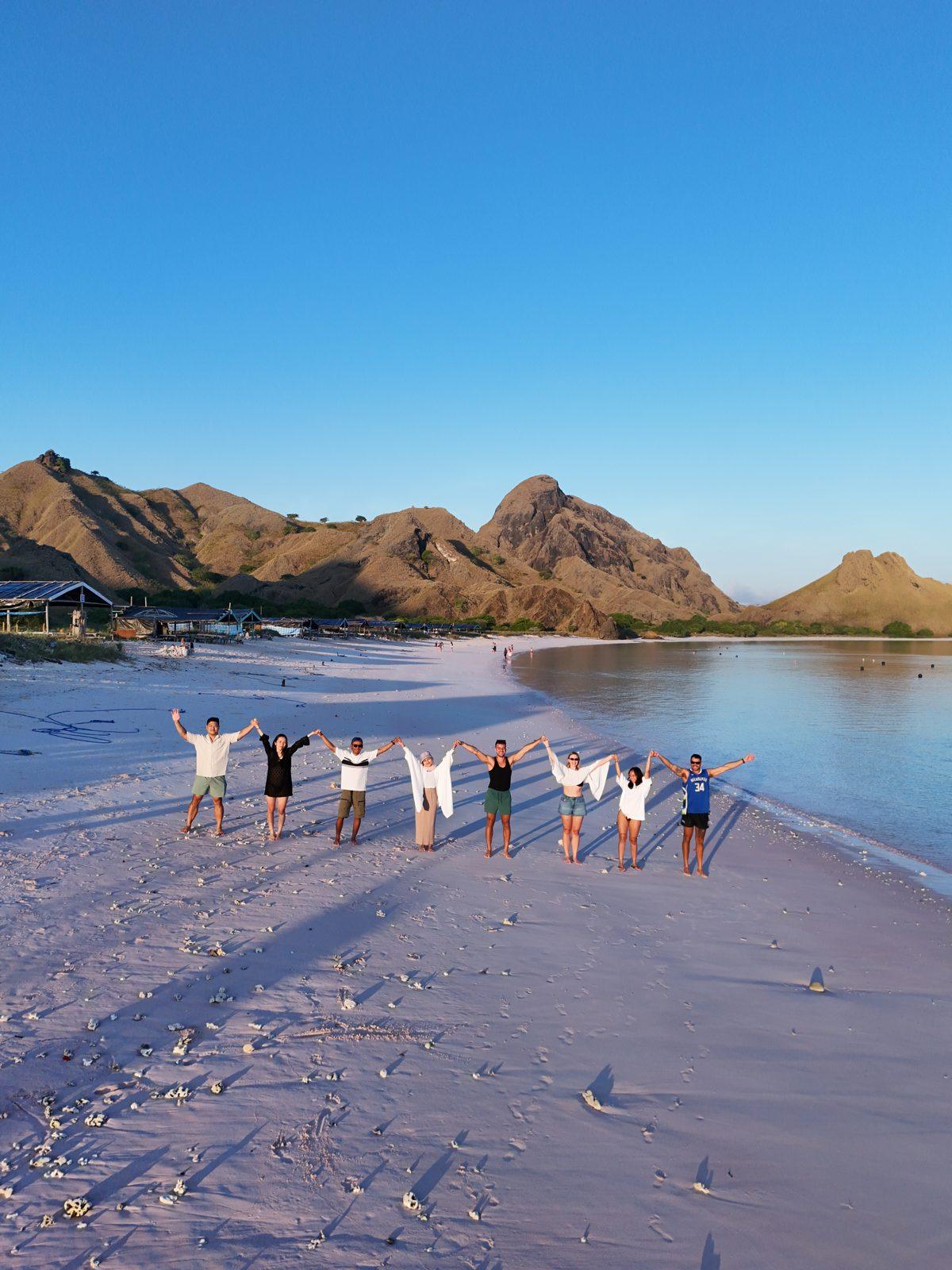 Pink Beach – Group in line on pink sand, hills behind (Real photo from a Komodo Explorer trip)
